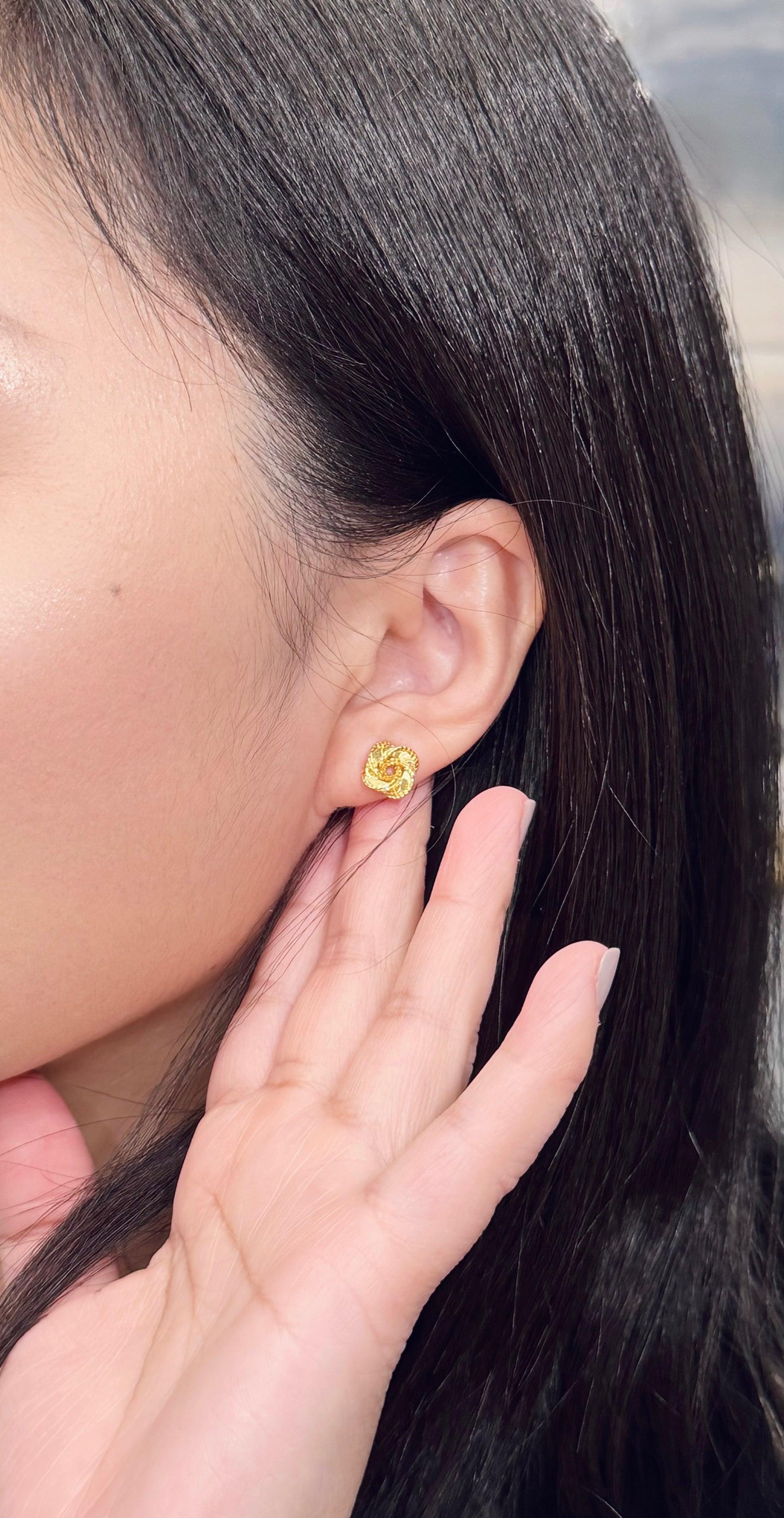 Close-up of a person wearing a gold color earring with a blurred background