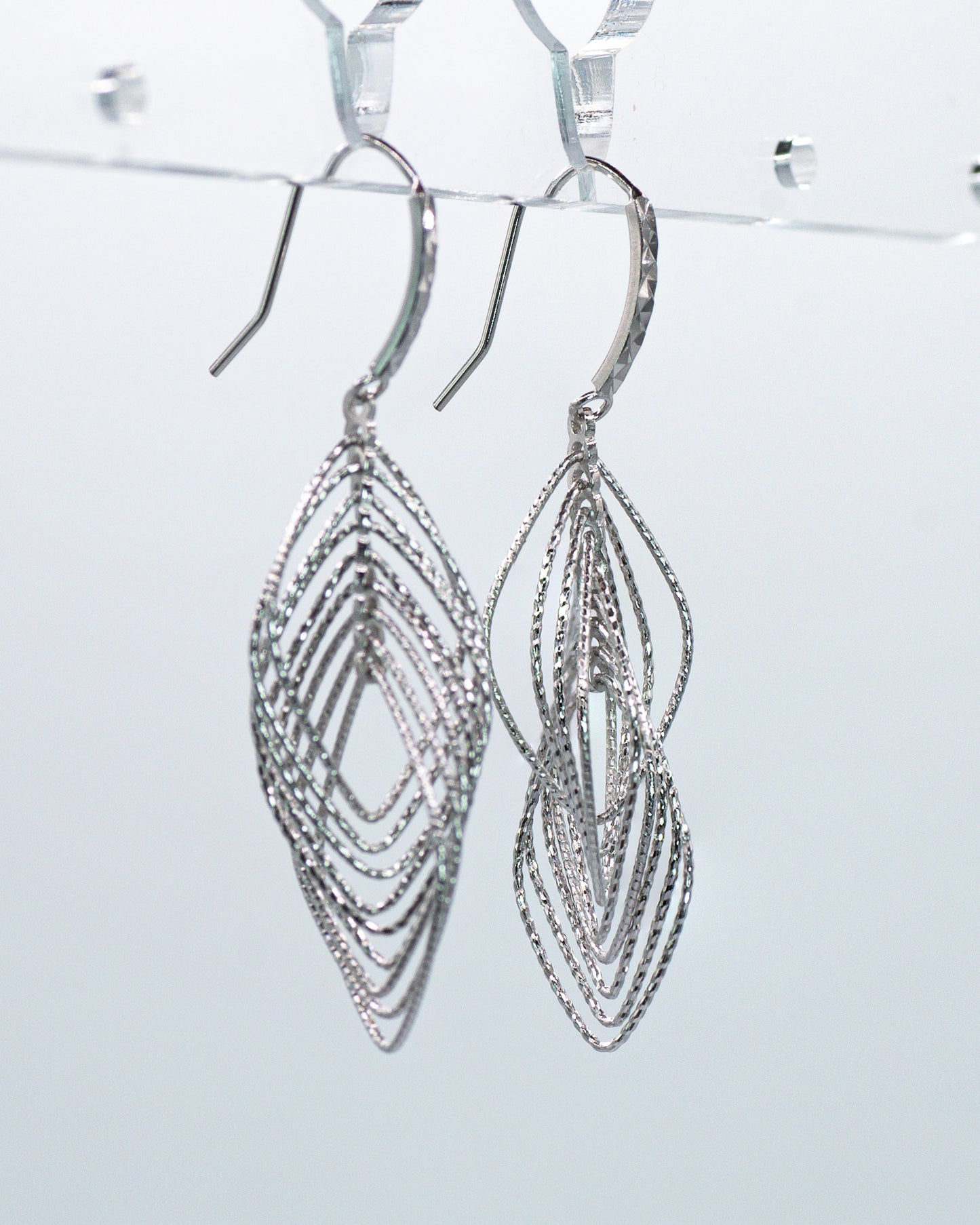 Silver earrings with intricate design on a light gray background