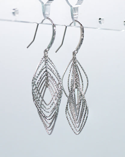 Silver earrings with intricate design on a light gray background