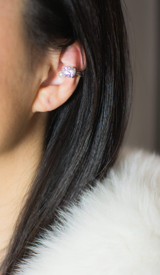 Close-up of an ear wearing a diamond earring with a blurred background